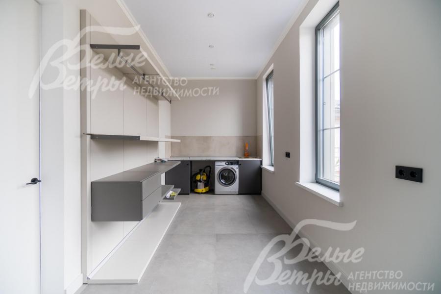 В постирочной с двумя окнами установлена стиральная машина