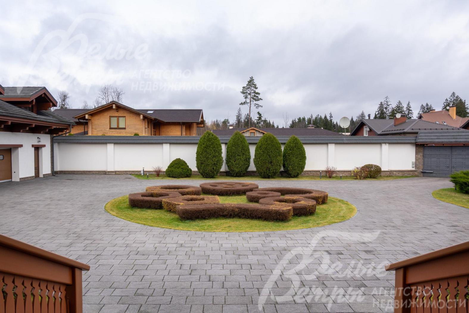 Перед главным входом - круглая клумба с кустами спиреи сложной конфигурации, парковка у дома рассчитана на более, чем 10 автомобилей