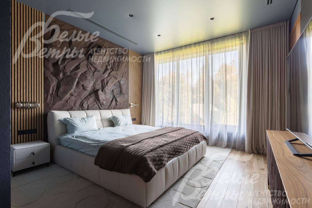 Одна из спален на втором этаже: стена у изголовья стилизована под скалу