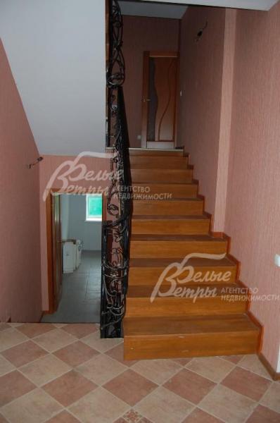 Широкая лестница с комфортной высотой ступеней отделана натуральным деревом и обрамлена шикарной ковкой