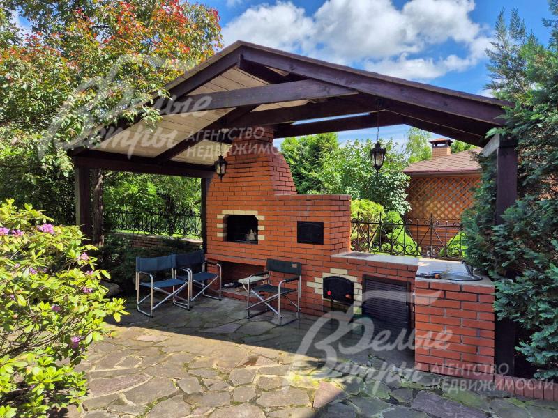 Зона барбекю на участке с печью-мангалом и водопроводом.