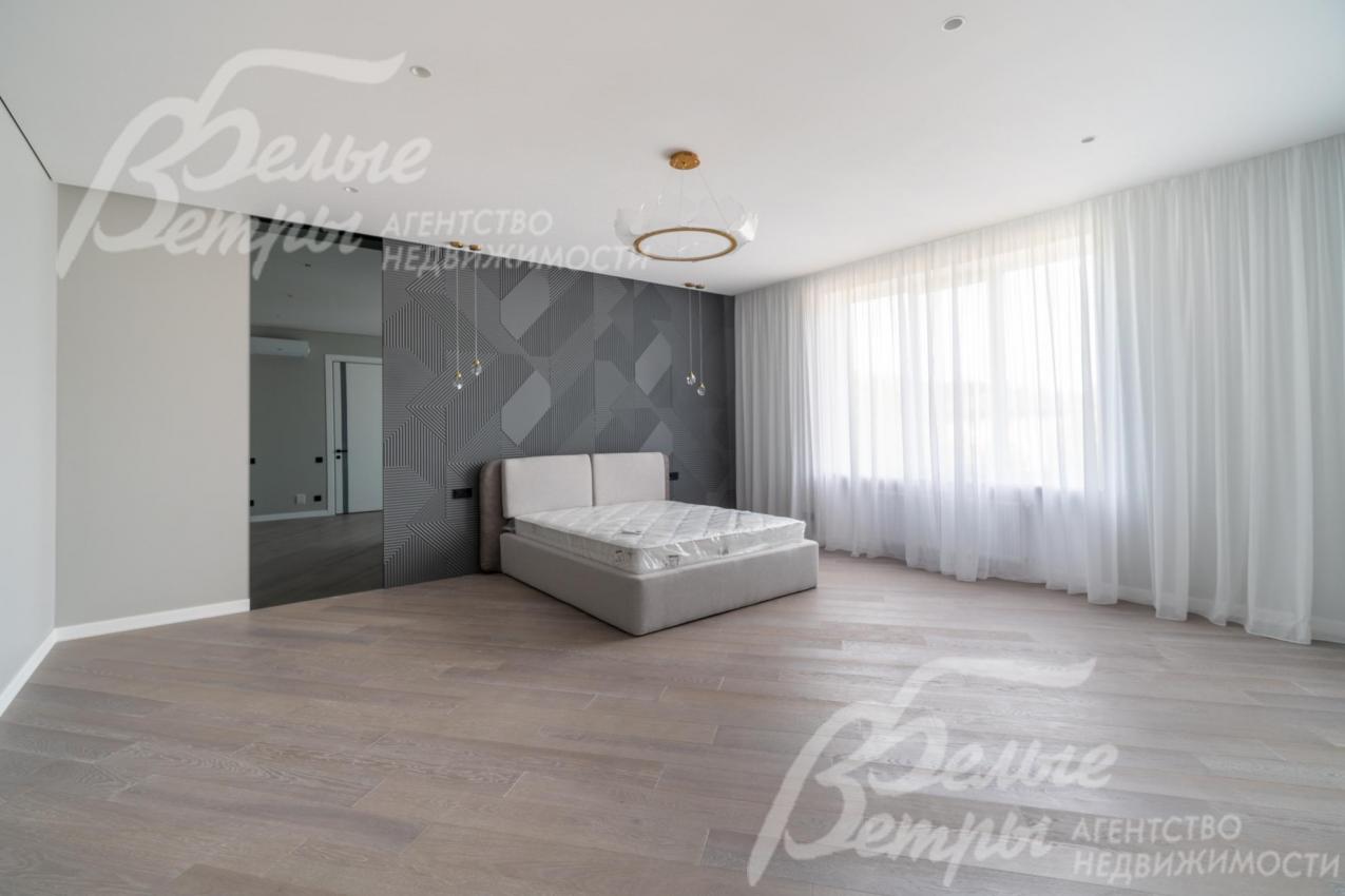 Просторная спальня на втором этаже с большим окном и кроватью