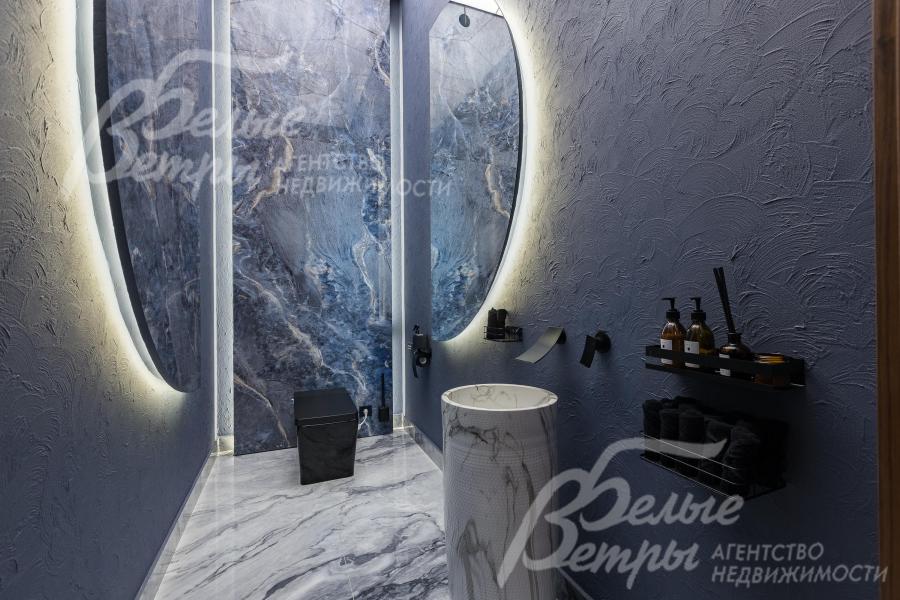 Санузел первого этажа с эффектной подсветкой и раковиной-стойкой под мрамор