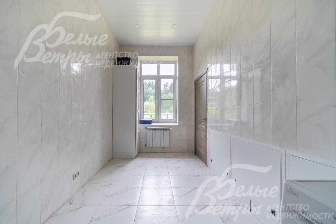 Постирочная на первом этаже отделана плиткой и панелями, установлена стиральная машина