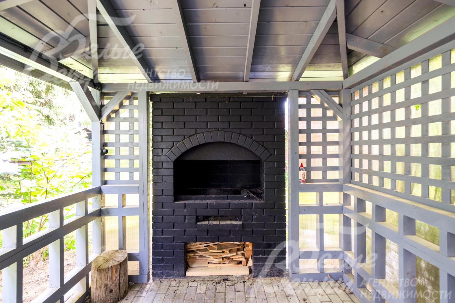 В беседке - большой кирпичный мангал с дровницей