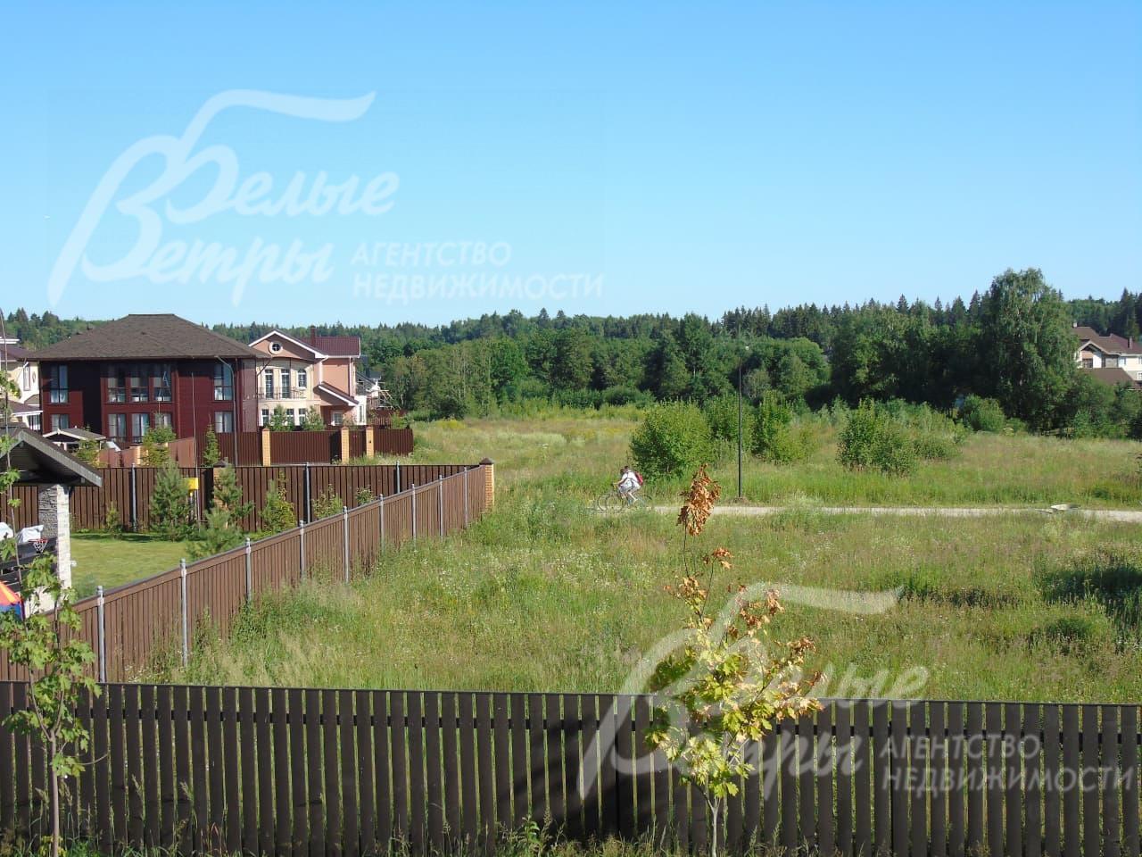 Участок огорожен высоким деревянным забором на кирпичных столбах