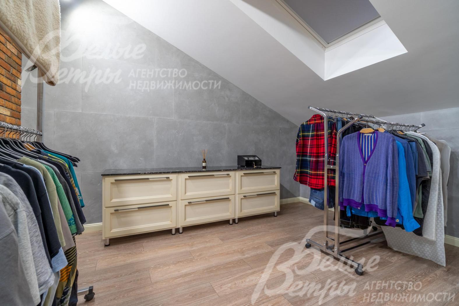 Гардеробная мастер-спальни с мансардным окном, оборудована системой хранения и рейлами