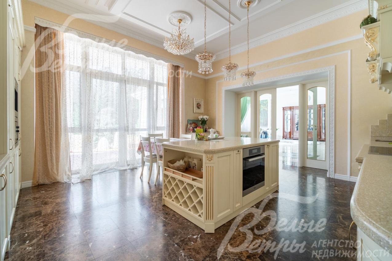 На кухне - итальянский гарнитур из массива дерева с фигурными карнизами, филёнчатыми фасадами, колоннами, позолотой. Из кухни есть выход на просторную террасу через стеклянный портал