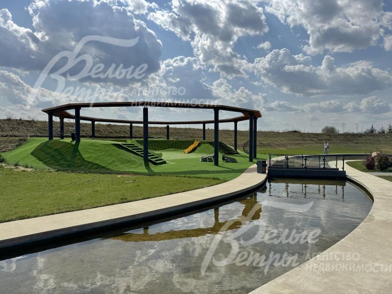 Территория коттеджного посёлка. Одна из рекреационных зон с ухоженным газоном и искусственным каналом