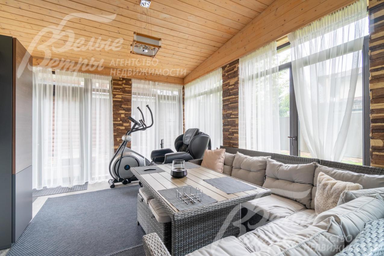 Застеклённая терраса на первом этаже с мебелью и широкоэкранным телевизором 