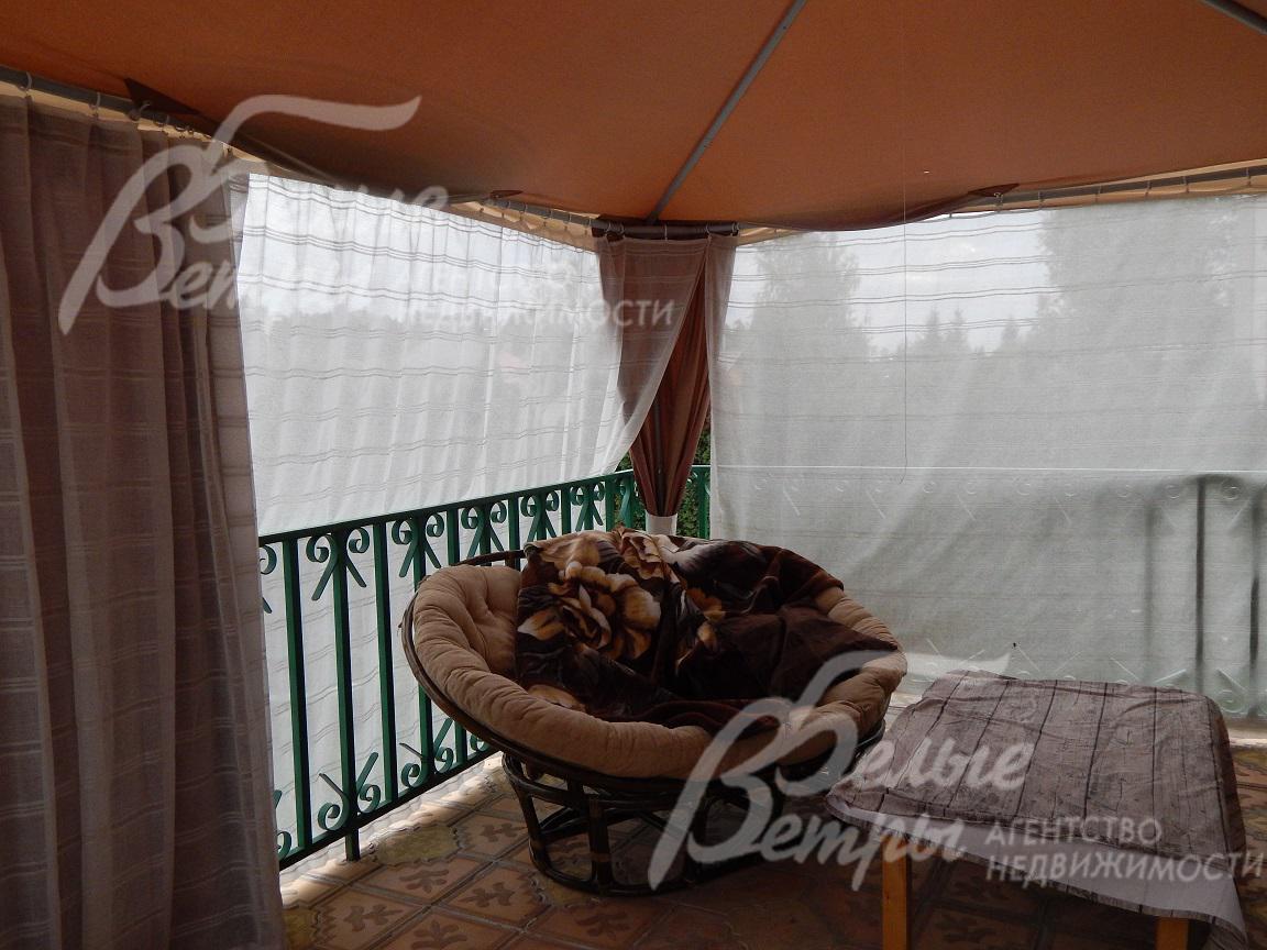 Шатер, установленный на террасе, укрывает уютное плетеное кресло и небольшой столик