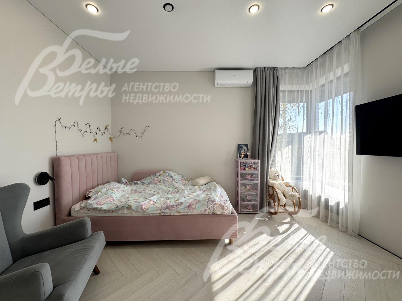 Одна из спален на втором этаже с кроватью, креслом, телевизором и окном углового типа