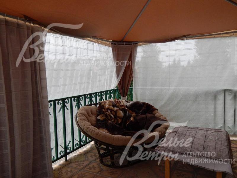 Шатер, установленный на террасе, укрывает уютное плетеное кресло и небольшой столик