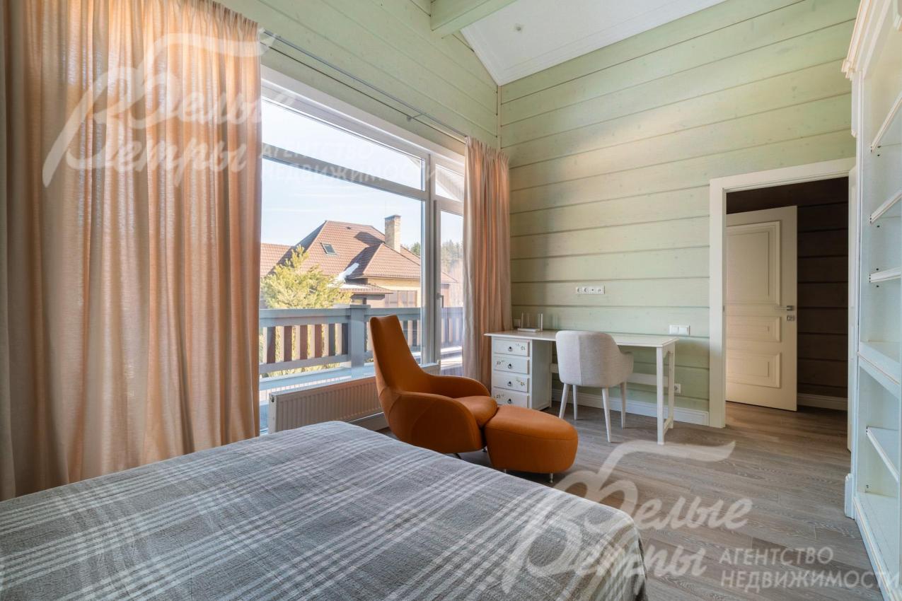 Одна из спален на втором этаже: в ней есть шкаф, туалетный столик, рабочее мест и удобное кресло