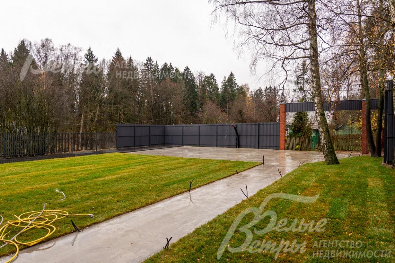 Участок огорожен высоким забором на бетонном основании, выполнена въездная группа