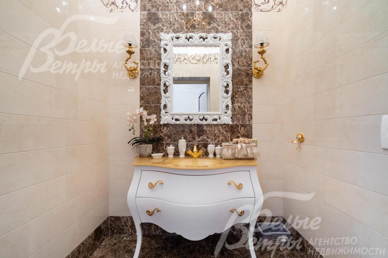 В холле установлен комод с крупным настенным зеркалом в массивной резной раме