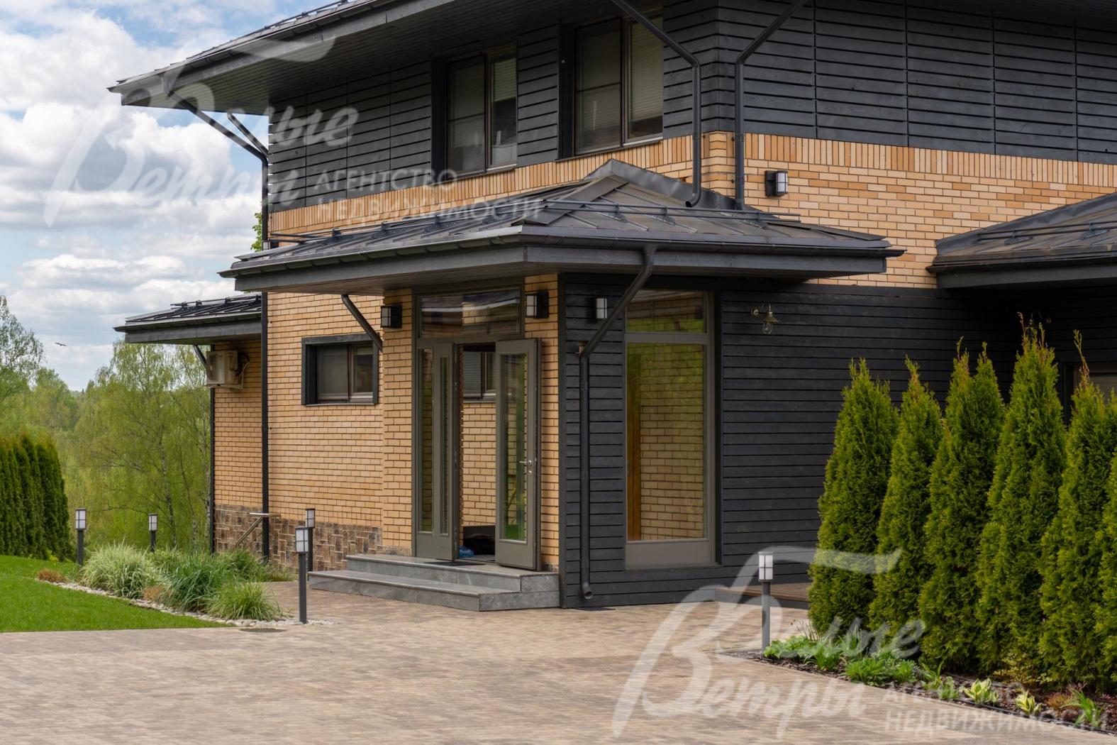 Стены дома облицованы кирпичом и обшиты доской из тонированной лиственницы