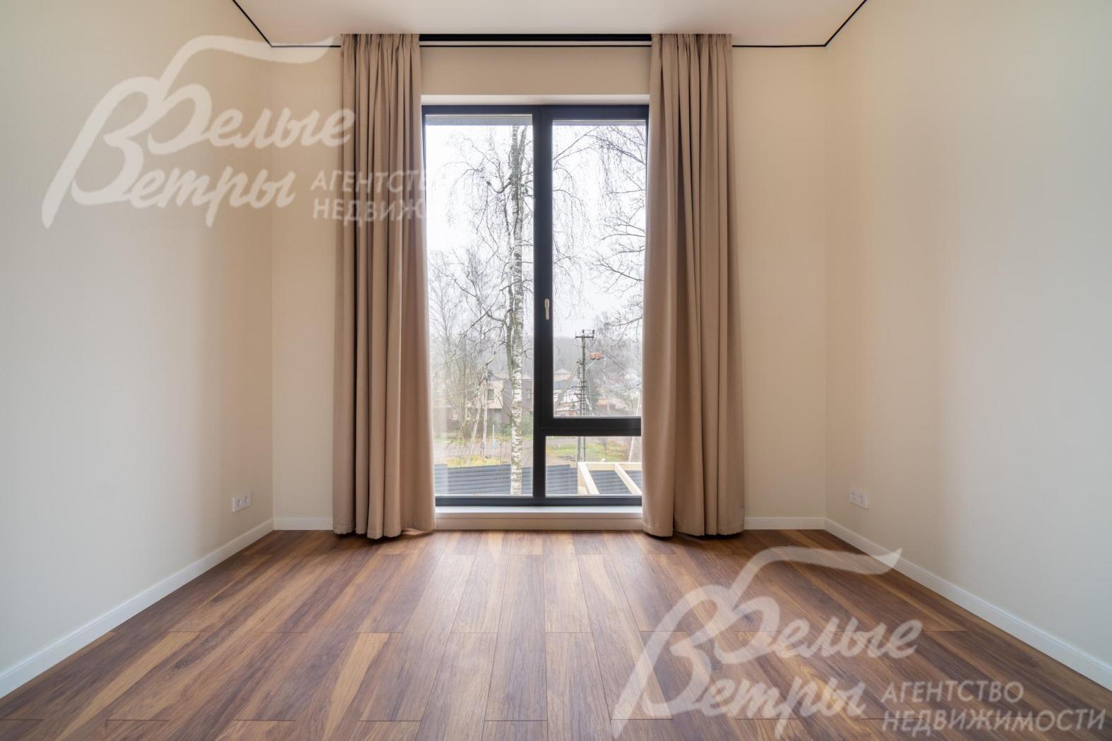 Одна из спален на втором этаже. Стены окрашены в светлый нейтральный оттенок, что визуально расширяет пространство и создаёт ощущение чистоты и свежести