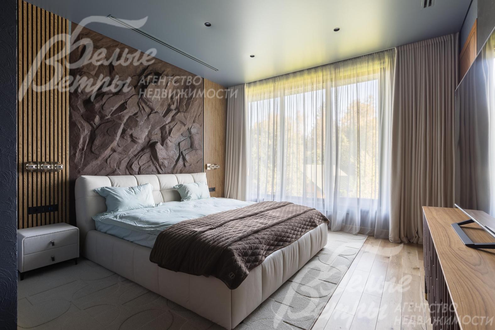 Одна из спален на втором этаже: стена у изголовья стилизована под скалу