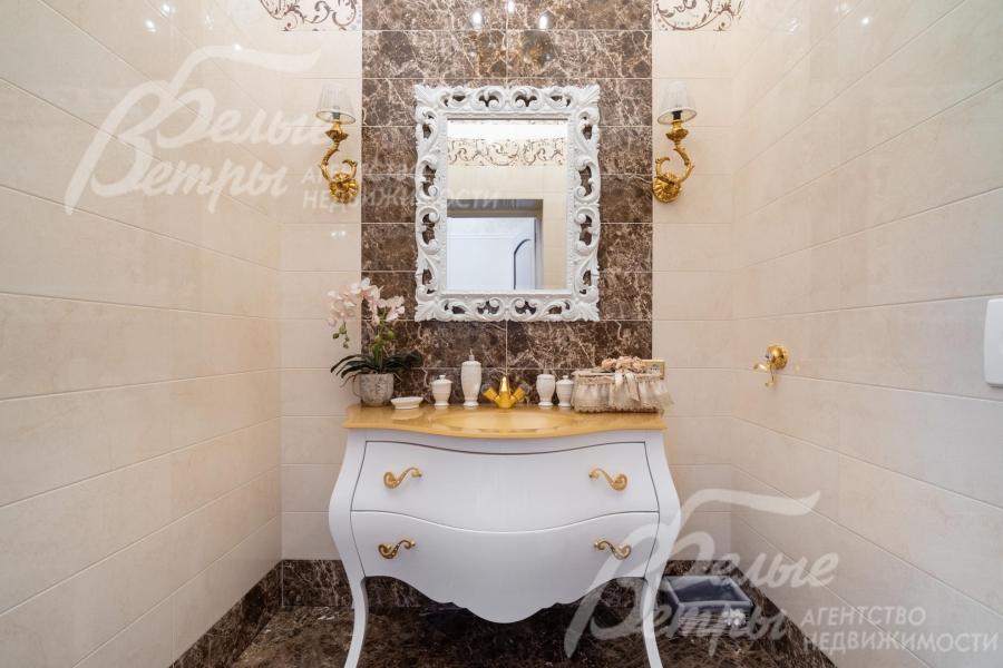 В холле установлен комод с крупным настенным зеркалом в массивной резной раме