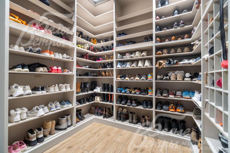 Одна из гардеробных выполнена в формате обувницы: предусмотрены полки для обуви, занимающие всю высоту помещения — от пола до потолка