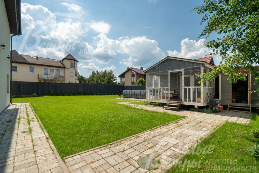 На участке стоит одноэтажный гостевой дом с крытой террасой