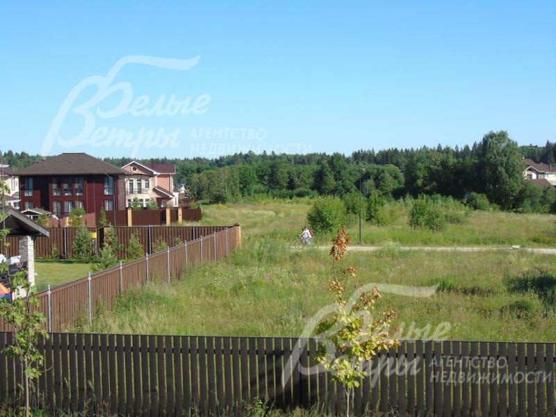 Участок огорожен высоким деревянным забором на кирпичных столбах